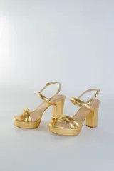 Sandalia de cuero con plataforma y taco cuadrado alto. Presenta una tira delgada en el tobillo con cierre de hebilla metálica y dos tiras acolchadas en la parte frontal.