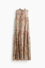 Vestido largo sin mangas de corte evasé, con cuello elevado, abertura en la nuca y tiras largas en la espalda. Cuenta con pollera acampanada con costura fruncida y diseño con estampado paisley en tonos multicolor.