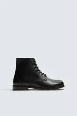 Bota tipo derby con cordones, confeccionada en piel lisa con horma cuadrada y suela con ligero tacón.