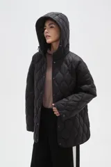 Campera acolchada de color negro con diseño capitoneado de ondas, manga larga, capucha integrada y cierre frontal con botones a presión.