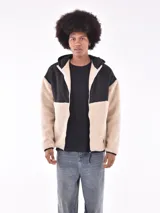Campera con cierre frontal, capucha y diseño de bloques de color. La parte principal del cuerpo y las mangas son de tejido de borrego (teddy) color beige claro, mientras que los hombros, la capucha y los bordes son de tela negra lisa.