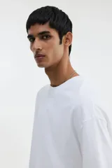 Remera blanca de algodón pesado, corte oversized, con cuello redondo ribeteado, hombros caídos y bajo recto.