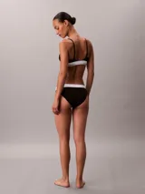 Bralette de triángulo Calvin Klein confeccionado en una mezcla de algodón, modal y elastano. Presenta copas ligeramente forradas sin aro, tirantes ajustables y la icónica banda elástica con el logo de la marca.