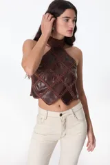 Top de cuello halter confeccionado con parches de cuero negro unidos mediante tejido de punto a crochet, creando un diseño geométrico de rombos.