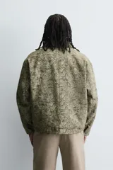 Cazadora de corte relajado con tejido jacquard de diseño abstracto en tonos verdes. Presenta cuello de solapa en pana a contraste, cierre frontal con cremallera, bolsillos frontales de plastrón y mangas largas con puños abotonados. Cuenta con interior acolchado.