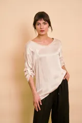 Blusa holgada de satén color beige, con escote en V y mangas largas con trabilla para sujetar remangadas.