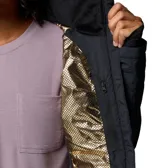 Campera técnica acolchada de color negro con capucha integrada. Presenta cierre frontal completo, bolsillos laterales con cremallera y puños con orificio para el pulgar. El diseño incluye costuras horizontales y diagonales que crean un patrón geométrico, con el logo de la marca bordado en el pecho.
