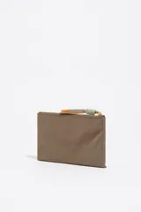 Billetera de estructura blanda confeccionada en nylon negro, con cierre de cremallera superior y bolsillo frontal con cierre. Presenta logo metálico dorado en el frente.