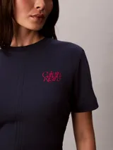 Remera Calvin Klein de manga corta y cuello redondo, color azul marino, confeccionada en algodón pima. Presenta costuras verticales en el frente y un sutil logo gráfico script bordado en color rojo en el pecho.
