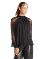 Blusa de encaje negro con cuello halter y mangas largas transparentes. Presenta un diseño elegante con detalles florales en el encaje y cierre con lazo en la espalda.