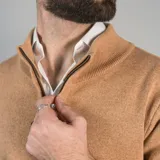 Campera tejida color marrón claro con cierre frontal, cuello alto y mangas largas con puños acanalados.