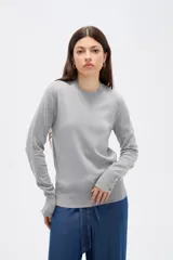 Sweater de lyocell al cuerpo, con cuello redondo a la base y mangas largas con detalle de botones en los puños.