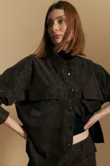 Sobrecamisa de efecto engomado en color negro, con textura lavada, cuello clásico, cierre frontal con botones a tono y bolsillos frontales con solapa.