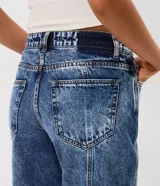 Pantalón de jean estilo wide leg con cintura media, cierre frontal con botón y cremallera, bolsillos funcionales y diseño de pierna amplia con recorte transversal.