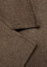 Abrigo largo de lana en color marrón, con diseño oversize, cuello con solapas de muesca y cierre frontal de doble botonadura. Cuenta con dos bolsillos laterales y mangas largas.