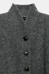 Abrigo largo gris melange de lana de la colección ZW de Zara, con cuello subido, cierre frontal abotonado y bolsillos con solapa en el delantero.