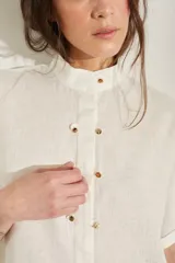 Vestido corto color beige de lino, con moldería amplia, manga corta, cuello mao y cierre frontal con botones dorados.