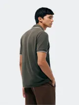 Remera polo blanca de manga corta, con cuello camisero y ribetes grises en cuello y puños. Cuenta con cierre frontal de botones y un pequeño logo bordado en el pecho.
