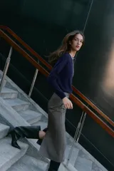 Falda midi tubo jaspeada en color gris oscuro, de tiro alto, con abertura en la espalda y cierre trasero con cremallera oculta.