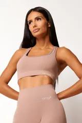 Conjunto deportivo de top nadador y calza larga de tiro alto en color tostado, confeccionado en tejido seamless con textura acanalada y efecto modelador.