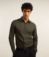 Camisa de manga larga confeccionada en tejido tricolina de algodón, con cuello inglés, cierre frontal abotonado y puños con botones.