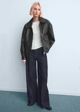 Pantalón de jean estilo wide leg de tiro alto, con diseño de cinco bolsillos, trabillas para cinturón y cierre frontal con cremallera y botón.