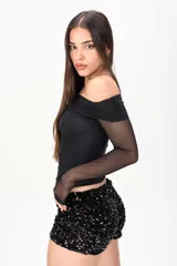 Top negro de manga larga confeccionado en tela semitransparente, con diseño off-shoulder y escote bote drapeado.