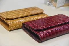 Billetera de cuero marrón con estampado de piel de serpiente, con cierre de broche a presión.