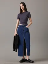 Falda larga de denim de algodón de peso medio, color azul índigo oscuro, con ajuste recto y abertura central delantera. Presenta diseño de cinco bolsillos y bragueta con cremallera.