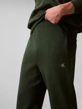 Pantalón jogger de felpa verde oscuro, con cintura elástica, bolsillos laterales y bajos ajustados en canalé. Incluye el monograma CK bordado en la pierna. Marca Calvin Klein.