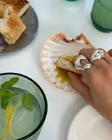 Anillo plateado con forma orgánica irregular y un agujero en el centro.