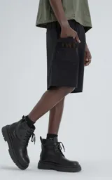 Bermuda técnica color negro, confeccionada en microfibra liviana, con cintura ajustable mediante cinturón integrado. Presenta múltiples bolsillos funcionales, incluyendo un bolsillo lateral con detalle de malla texturizada.