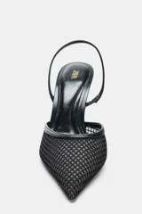 Zapato destalonado de tacón alto fino, color negro, con cuerpo principal de rejilla y puntera afilada. Presenta ribetes en material liso y tira trasera elástica para ajuste.