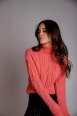 Suéter tejido de punto trenzado color salmón, con cuello alto y mangas largas. Corte ajustado al cuerpo.