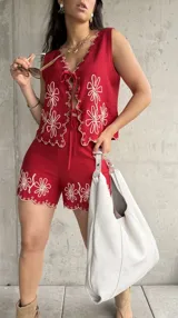 Chaleco rojo con bordado de flores blancas, escote en V con ajuste de lazo y borde festoneado.