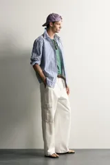 Camisa relaxed fit confeccionada en tejido de algodón, con diseño de rayas verticales en tonos azul y blanco, cuello con botones y manga larga.