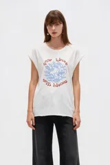 Remera de algodón blanca de corte holgado, cuello redondo y mangas cortas con vuelta. Cuenta con un estampado frontal circular en tonos azul y rojo con la leyenda "New ideas will bloom" y diseño floral.