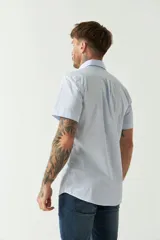 Camisa de manga corta con estampado de cuadros vichy en azul y blanco. Presenta cuello con botones, cierre frontal con botones y logo bordado en el pecho.