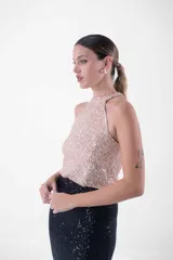 Vestido largo con cuello halter enteramente cubierto de lentejuelas, que combina un cuerpo superior en tono rosado y una falda larga en color negro.