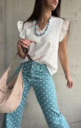 Musculosa blanca de diseño ligero con escote en V y sutiles detalles bordados tonales en el frente, complementada con volados en las sisas.
