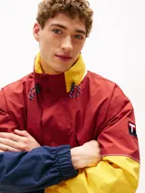 Campera de nailon con diseño color block en rojo, amarillo y azul marino. Tiene cuello alto, cierre de cremallera oculto con botones a presión, puños y bajo elásticos, dos bolsillos ribeteados en la cintura y logo de Tommy Hilfiger en la parte delantera, la trasera y las mangas.
