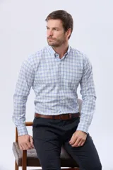 Camisa de manga larga con diseño a cuadros en tonos celeste, azul y blanco, con cuello abotonado y cierre frontal con botones.