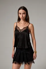 Top negro de tirantes finos con reguladores, confeccionado en poliéster con detalles de encaje y apliques de strass. Presenta escote en V y diseño entallado.