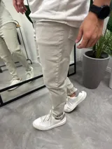 Jean de corte ajustado tipo skinny, color beige, con cierre frontal y bolsillos laterales. Confeccionado en tejido con elasticidad.