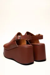Sandalias con plataforma color marrón, con capellada envolvente, pulsera trasera ajustable y hebilla metálica.