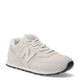Championes urbanos New Balance modelo 574, color marfil, confeccionados en gamuza y malla con detalles texturizados en la puntera. Presentan el logo N característico en los laterales y suela con diseño moteado.