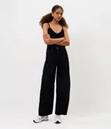 Pantalón de jean corte barrel con piernas anchas y cintura cónica. Presenta trabillas en la cintura, cierre frontal con botón y cremallera, bolsillos funcionales en frente y espalda, y detalle de recortes en las rodillas.