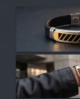 Pulsera de diseño moderno compuesta por una banda de goma negra y una placa central de acero inoxidable con detalles en baño de oro y aberturas geométricas. Incluye cierre de seguridad de acero.