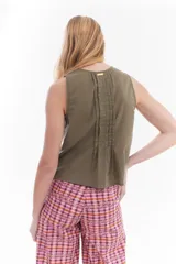 Blusa blanca sin mangas de algodón, con diseño de tablas frontales y escote con lazos para atar.