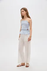 Top de algodón con diseño estampado de cuadros vichy en tonos celeste y blanco, corte al cuerpo con escote recto y tirantes finos. Presenta cuerpo fruncido tipo smock con cordones ajustables en los laterales que forman un pequeño volado en el ruedo.
